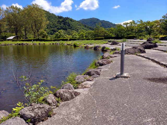 夏の緑の村。鯉の泳ぐ池と山並み